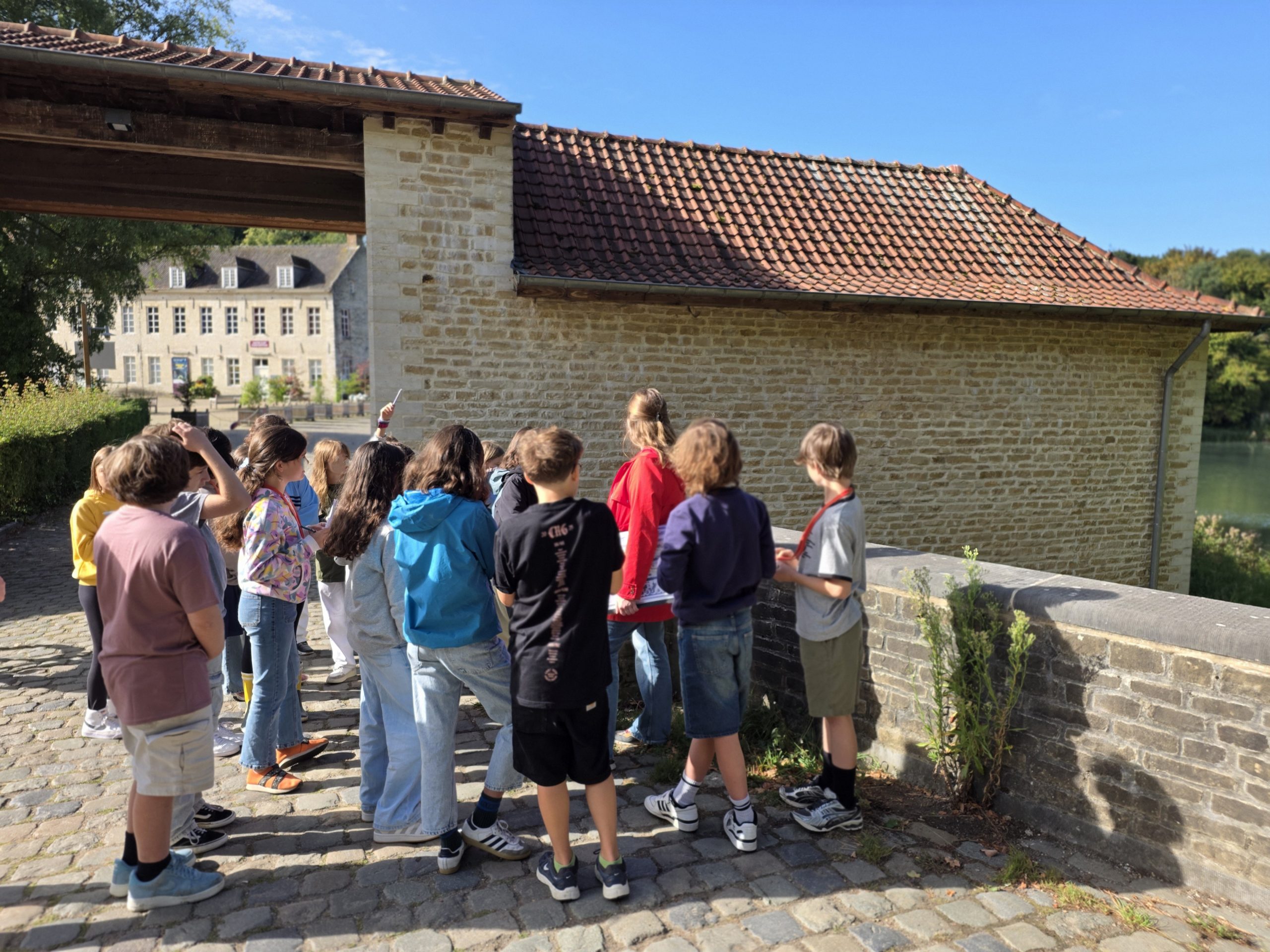 Un groupe d'élèves observe le mur du porche de l'entrée du site de Rouge-Cloître.