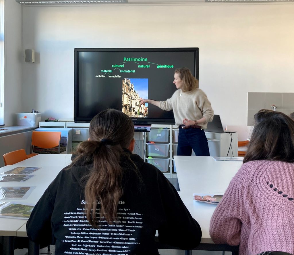 une collaboratrice des Classes du Patrimoine montre une rue, une enfilade de façades sur l'écran d'un smartboard
